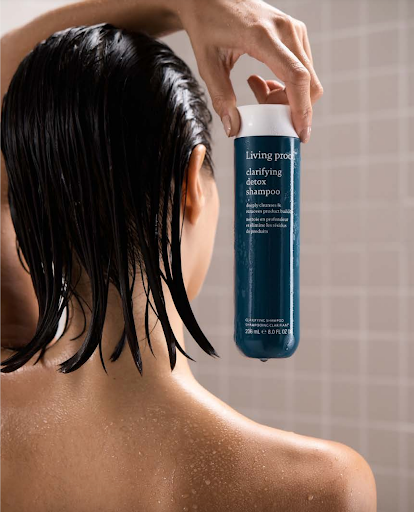 women holding clarifying detox shampoo in the shower